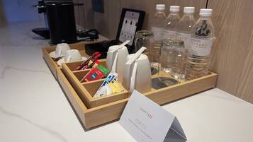A hotel room's breakfast setup with a tray containing cups, utensils, and bottled water.