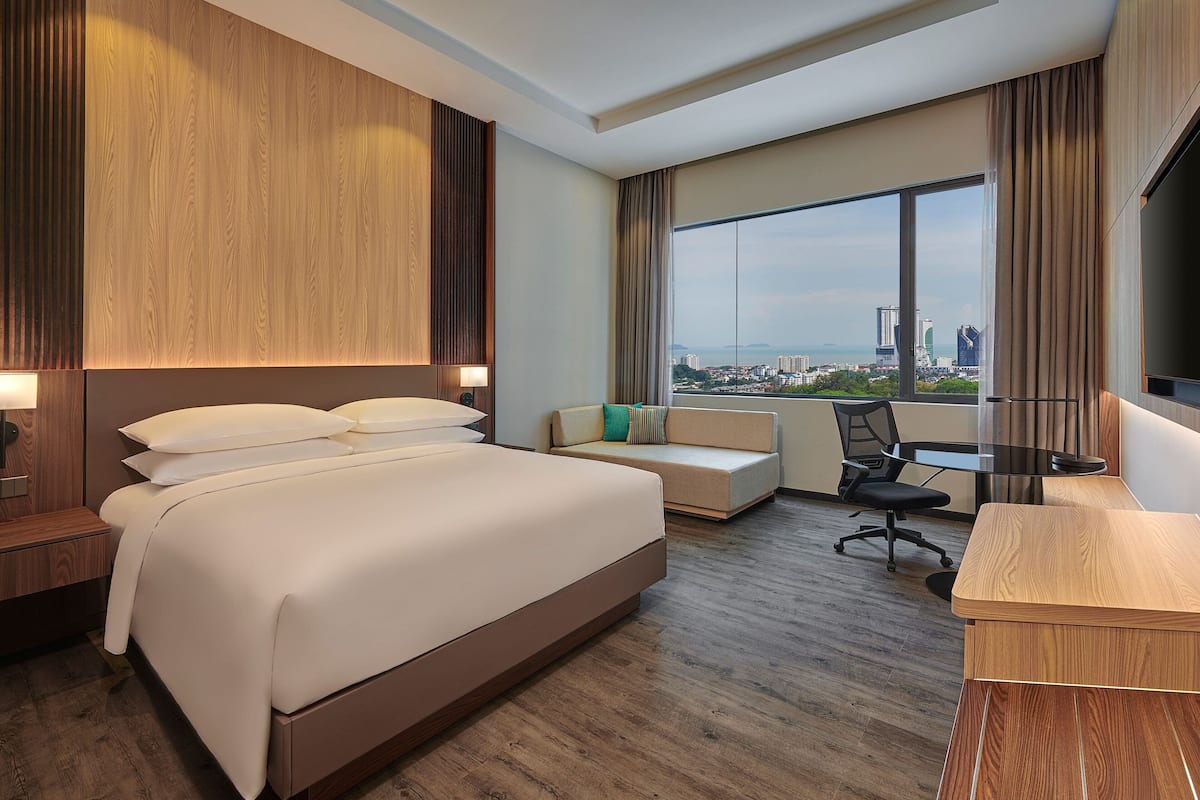 Une chambre d’hôtel avec un grand lit, un canapé, un bureau et une vue sur le paysage urbain.