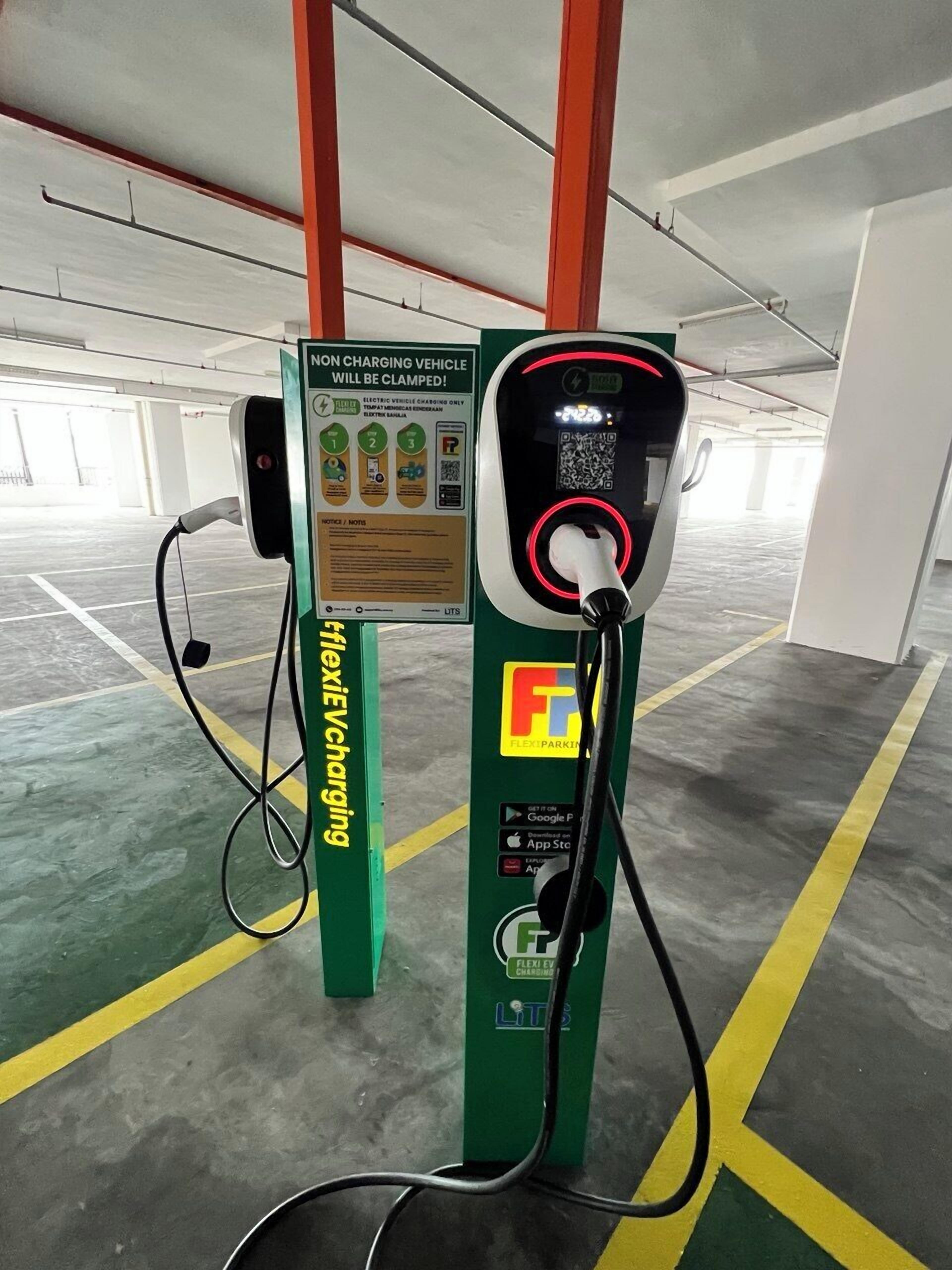 Uma estação de carregamento para veículos elétricos numa garagem de estacionamento, com um aviso de que o veículo será rebocado.