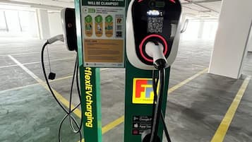 Uma estação de carregamento para veículos elétricos numa garagem de estacionamento, com um aviso de que o veículo será rebocado.
