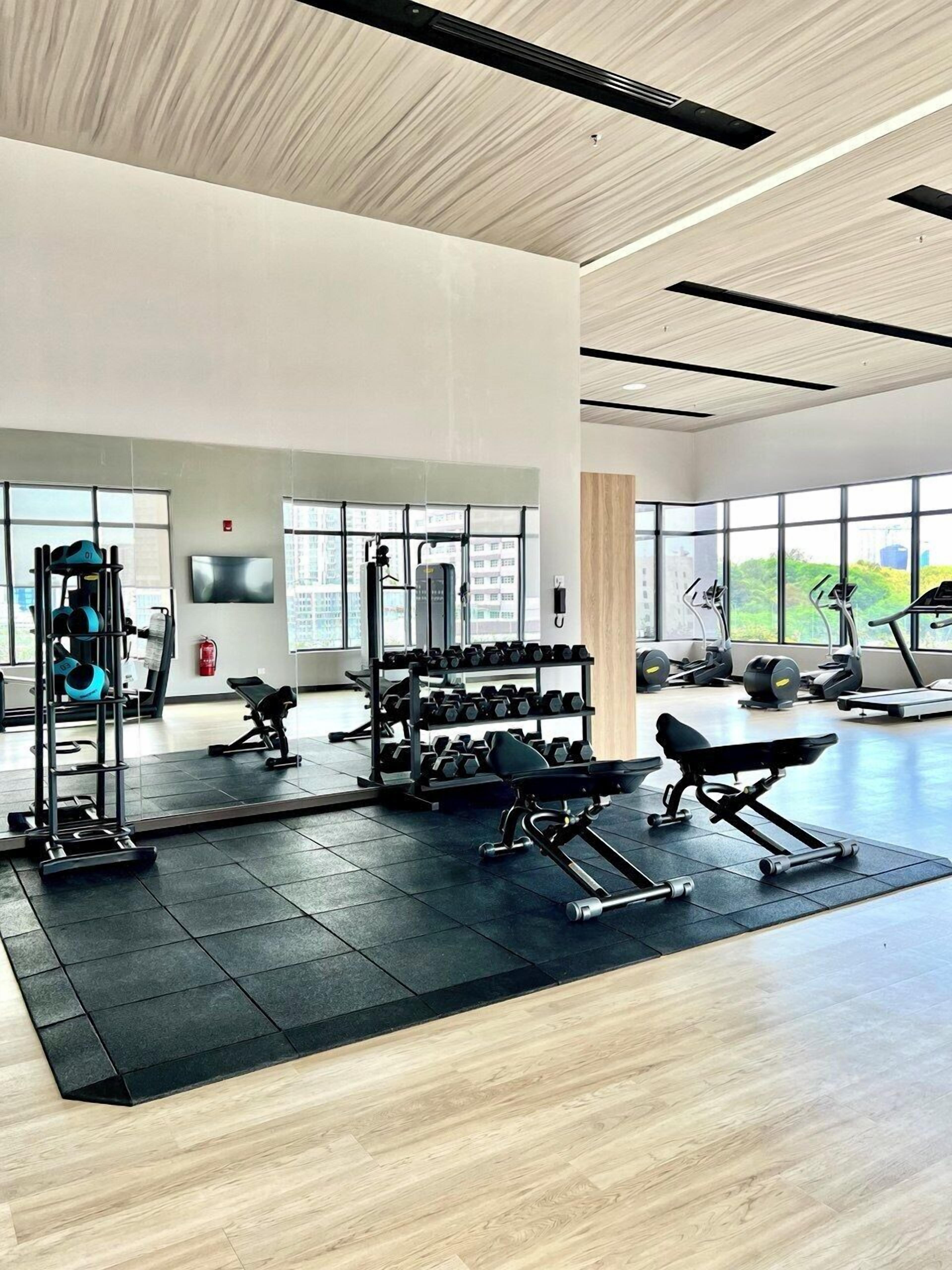 Un gimnasio moderno con diverso equipo de ejercicio, amplias ventanas y un diseño limpio y espacioso.
