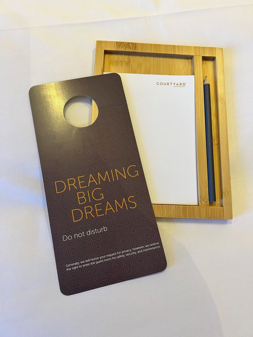 A wooden frame with a card and a pen. The card reads "DO NOT DISTURB" and "COUNTRYARD."