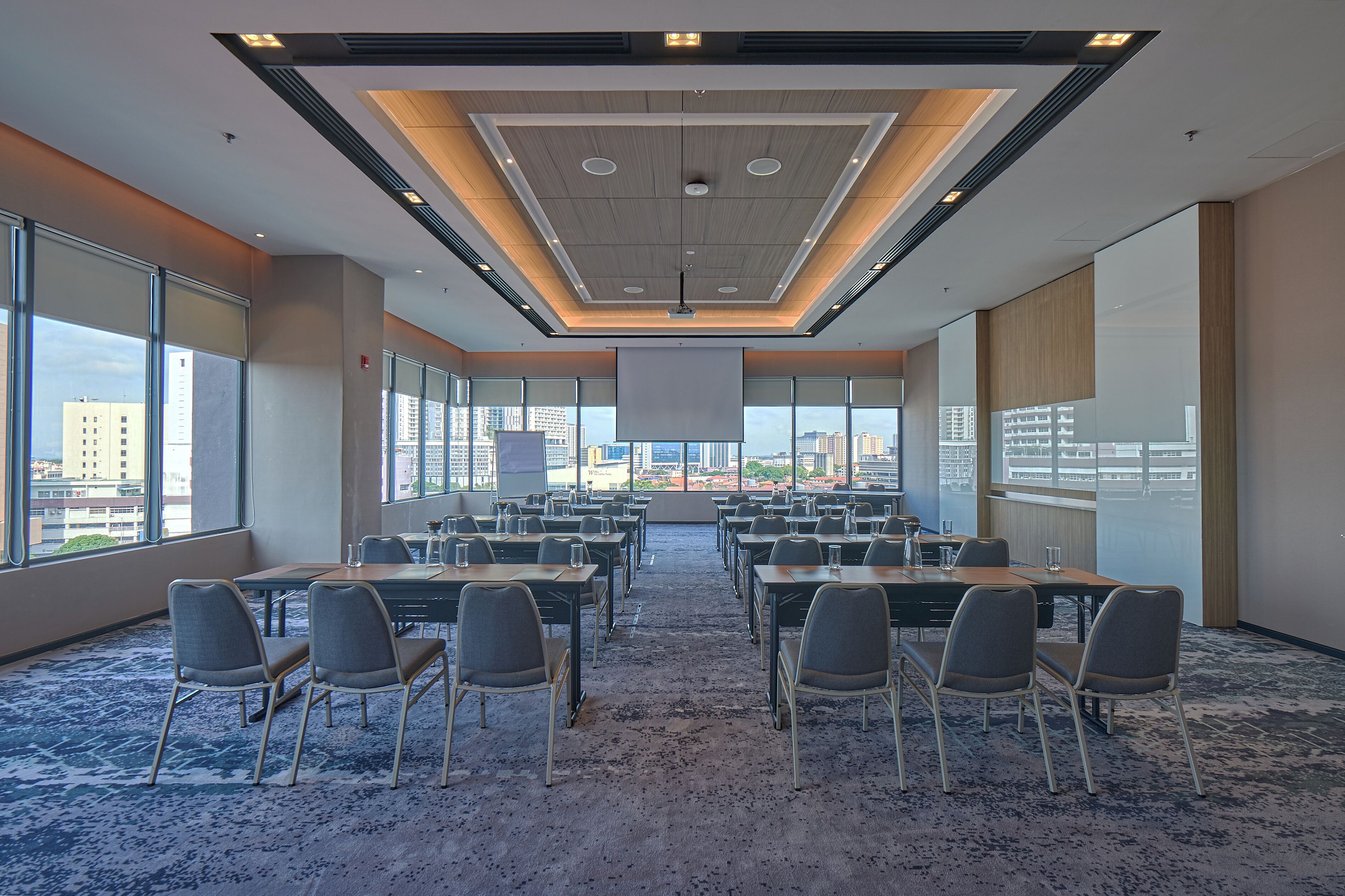 A conference room with a city view, large windows, and a carpeted floor.
