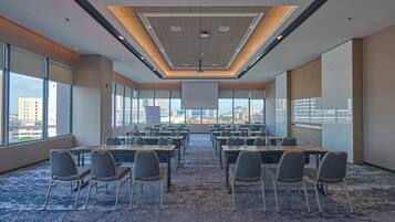 A conference room with a city view, large windows, and a carpeted floor.