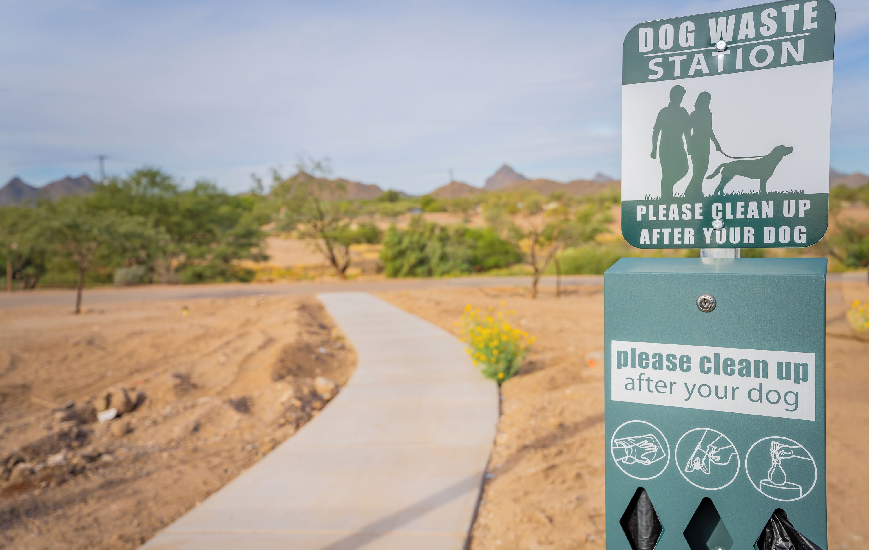 A dog waste station sign with instructions to clean up after your dog.
