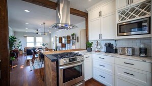 A modern kitchen with white cabinets, stainless steel appliances, and a wooden island.