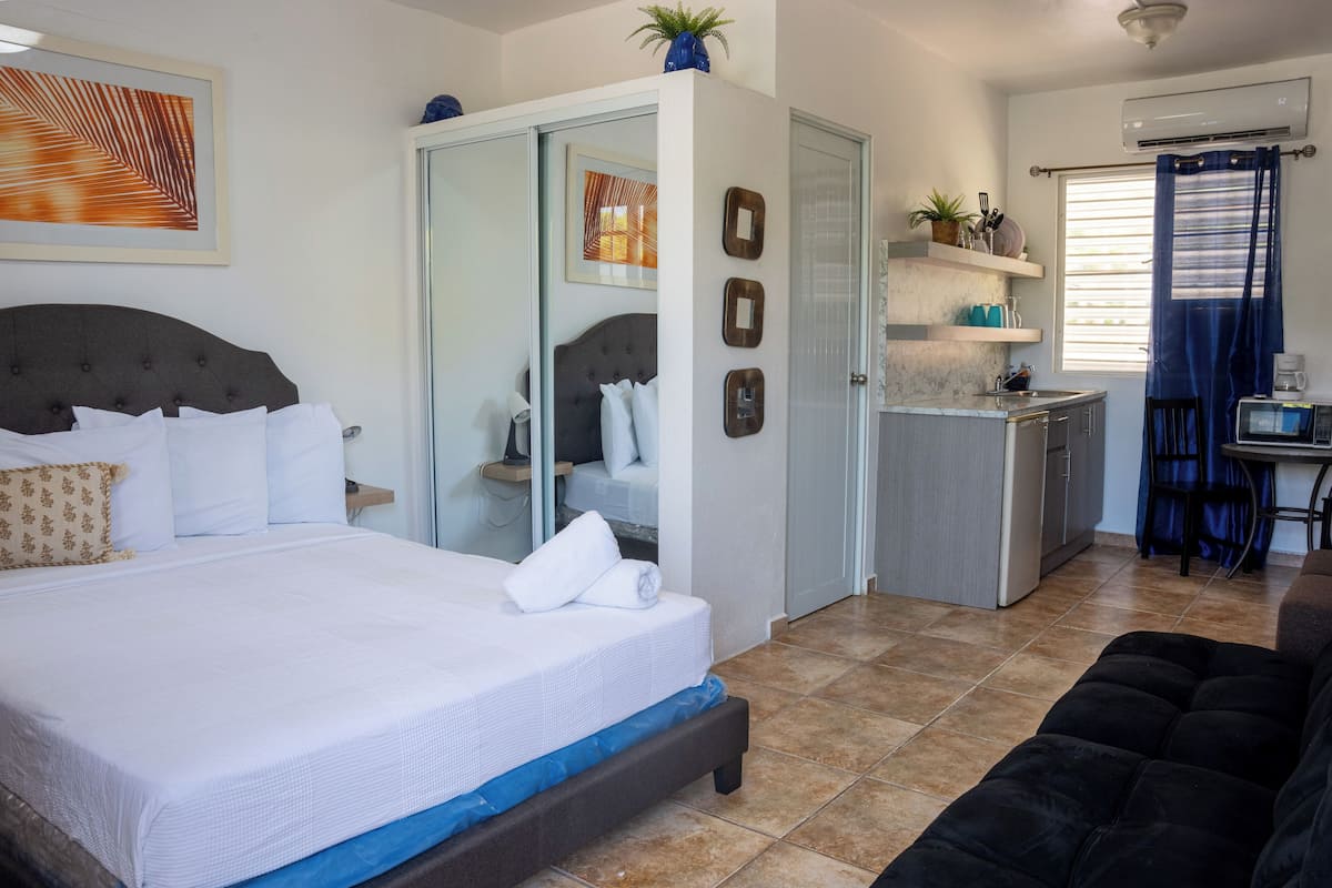 Un dormitorio con cama, armario, escritorio y kitchenette.