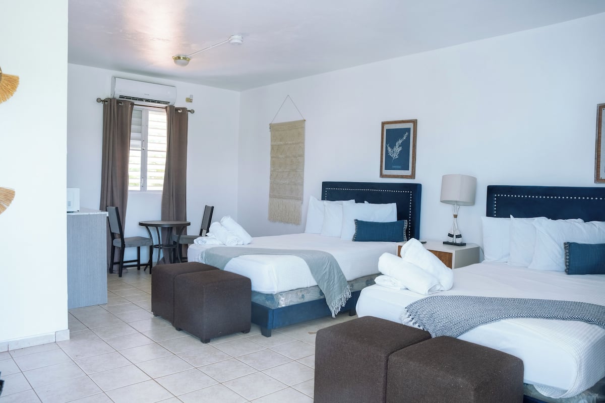 Habitación de hotel con dos camas, un escritorio, una silla y una mesita.