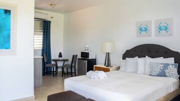 Habitación de hotel con cama, escritorio, silla, microondas, lámpara y obras de arte en la pared.