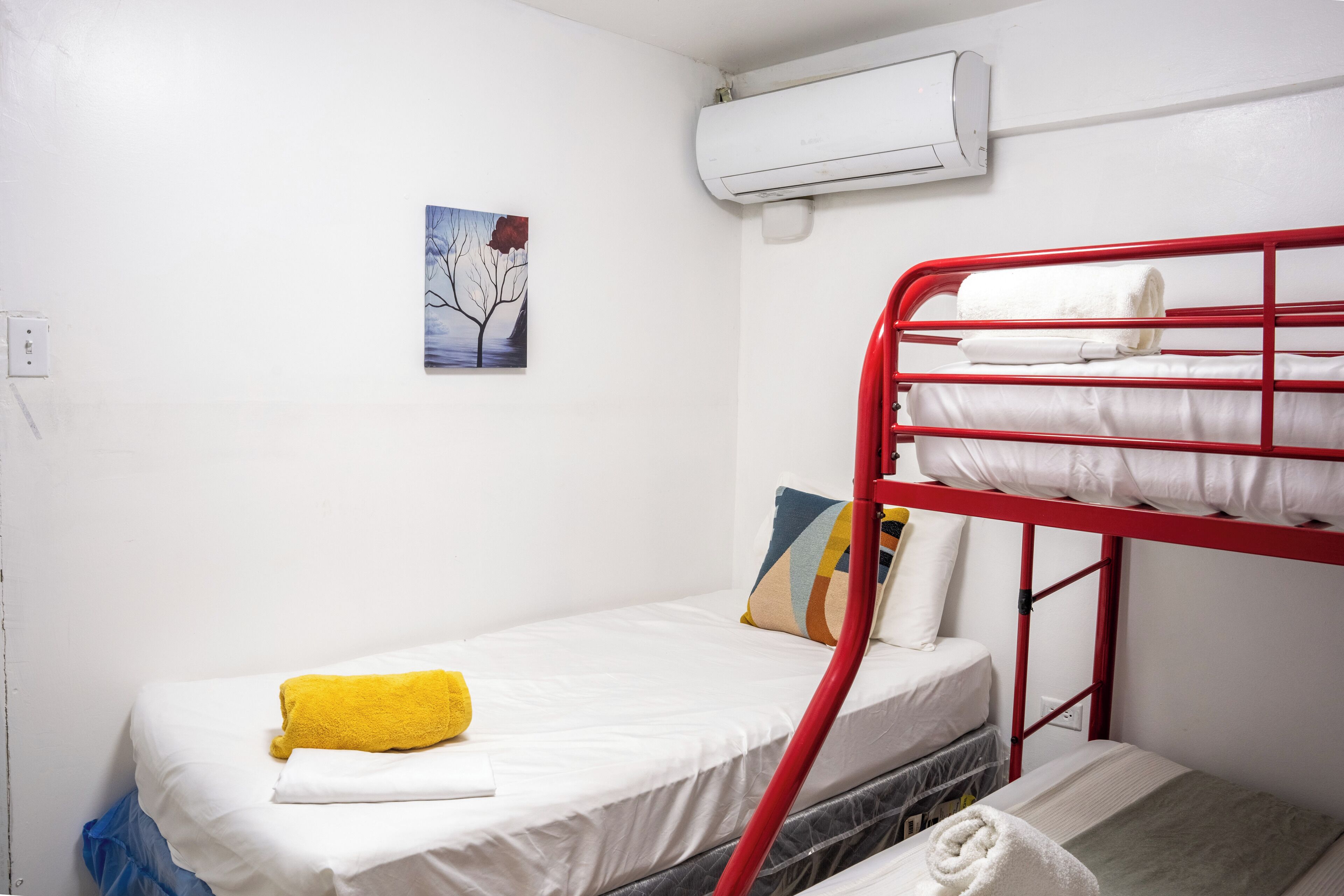 Ein Schlafzimmer mit Etagenbetten, einer weißen Matratze, einem gelben Handtuch und einem Bild an der Wand.
