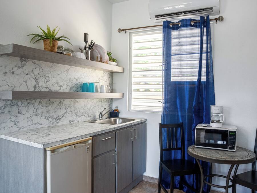 A compact kitchen with a marble backsplash, a built-in dishwasher, and a small dining area with a table and chairs.