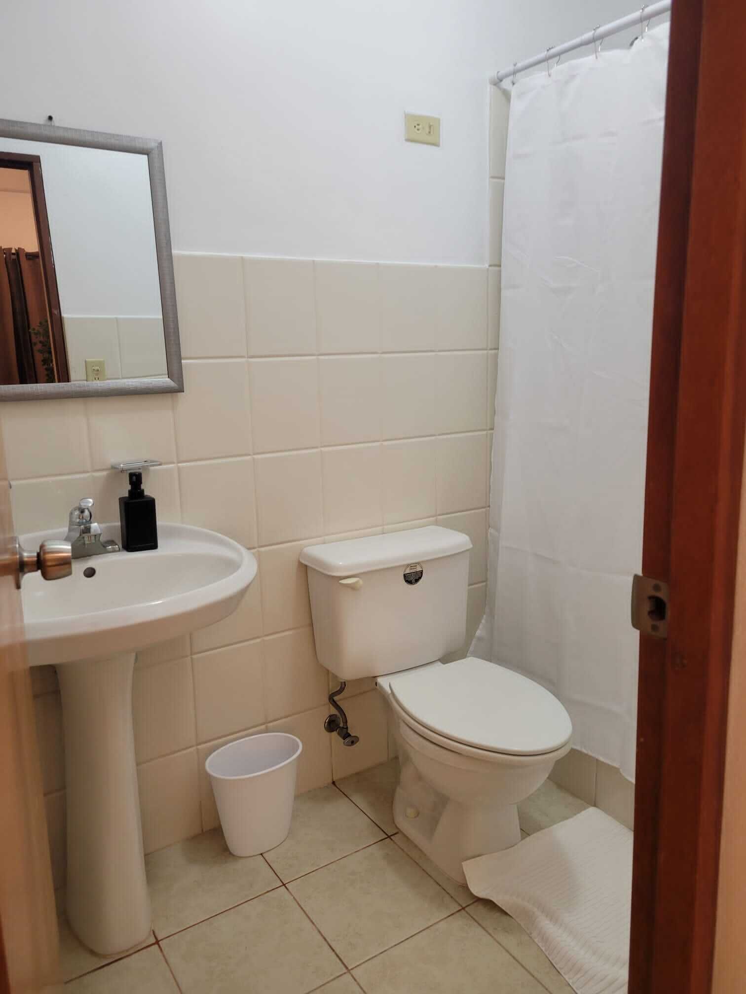 A bathroom with a sink, toilet, and a shower curtain.