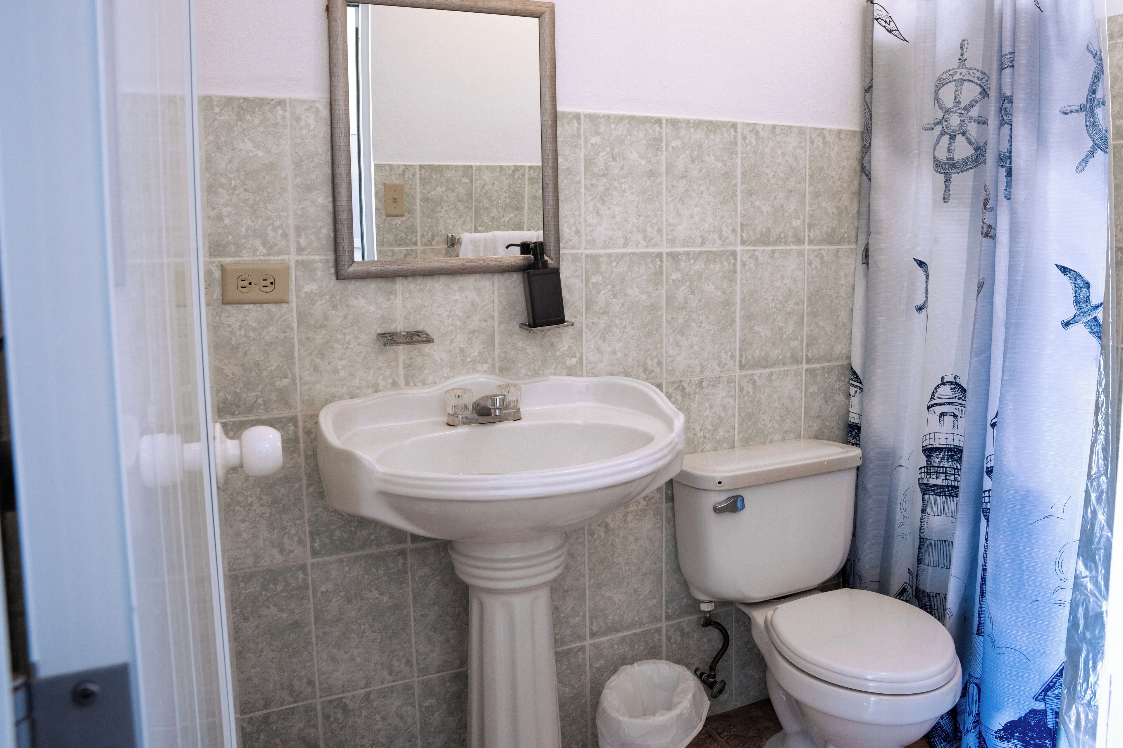 A bathroom with a pedestal sink, toilet, and a mirror above the sink.