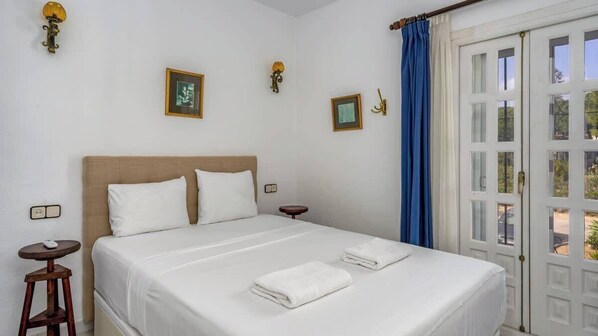 A neatly made bed with white linens, a wooden headboard, and two bedside tables with lamps.