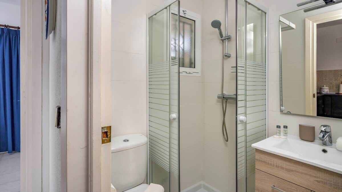 Une salle de bain moderne avec une douche à parois de verre, un lavabo blanc et un meuble-lavabo en bois.