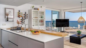 Une cuisine moderne dotée d’un grand îlot central, d’un meuble à vin et offrant une vue sur l’océan.