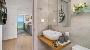 A modern bathroom with a large white sink, a mirror, and a glass shelf with flowers. - Lux Apt Med One by Costarentals - Ref 191 (Fuengirola)