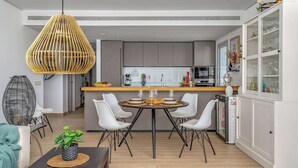 Une cuisine moderne avec un îlot central, des chaises blanches et un luminaire suspendu.