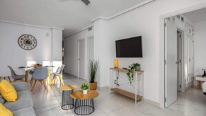 A modern living room with a sofa, coffee table, TV, and dining area. - Miraflores with pool by Costarentals - Ref 146 (Las Lagunas de Mijas)