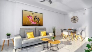 A modern living room with a grey sofa, yellow cushions, a coffee table, and a dining area with a table and chairs. - Miraflores with pool by Costarentals - Ref 146 (Las Lagunas de Mijas)