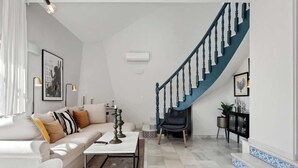 Ein modernes Wohnzimmer mit einem weißen Sofa, einem Couchtisch und einer Treppe mit blauen Geländern.