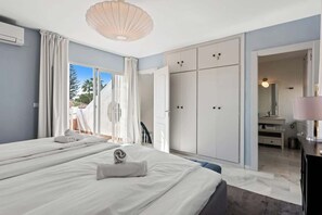 A hotel room with two beds, a large wardrobe, and a bathroom visible through an open door. - Townhouse with Pool by Costarentals- Ref 199 (Las Lagunas de Mijas)