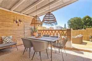 An outdoor patio with a wooden table, wicker chairs, and a cushioned sofa. - Townhouse with Pool by Costarentals- Ref 199 (Las Lagunas de Mijas)