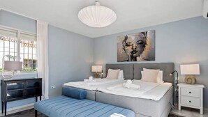 Ein modernes Schlafzimmer mit einem großen Bett, einer Bank, einem Schreibtisch und einem Fenster mit Vorhängen.