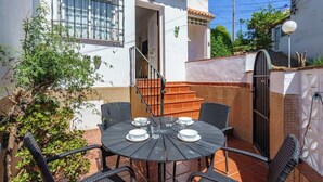 Eine Terrasse mit einem runden Tisch, vier Stühlen und einer Treppe, die zu einer Tür führt.