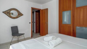 Ein Hotelzimmer mit einem Bett, einem Sessel, einem Holzschrank und einem Spiegel an der Wand.