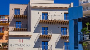Un hôtel à plusieurs étages, doté de balcons et d’une enseigne indiquant « HÔTEL ROCCAREGINA ».