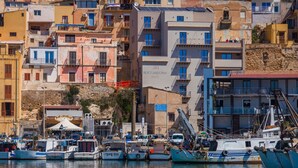 Une ville côtière dotée d’un port de plaisance, comprenant des bateaux et un hôtel appelé « ROCCAREGINA HOTEL ».