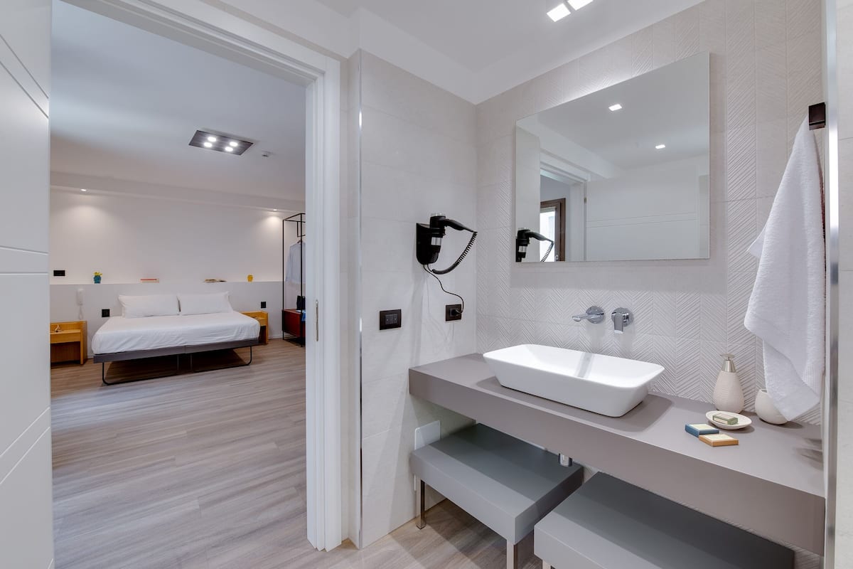 Un baño moderno con un espejo grande, un lavamanos blanco y una toalla colgada en la pared.