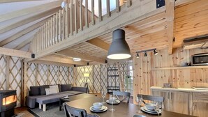 Un interior de cabaña acogedor con comedor, sofá y chimenea.