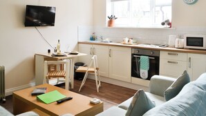Une cuisine moderne avec un coin repas, un téléviseur fixé au mur et une fenêtre donnant sur un paysage agréable.