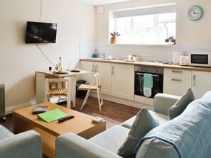 Una cocina moderna con comedor, televisor montado en la pared y ventana con vistas.