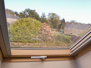 Une fenêtre de toit donnant sur un quartier résidentiel, avec vue sur des maisons et des arbres.