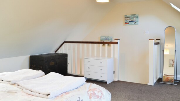 Une chambre à coucher comprenant un lit, une commode, une commode à tiroirs, un miroir et un tableau accroché au mur.