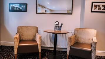 Two armchairs, a small round table, and a mirror on a wall with patterned carpet.