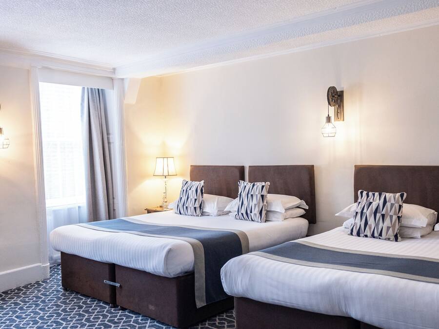 Quarto de hotel com duas camas, um tapete estampado e teto com design decorativo.