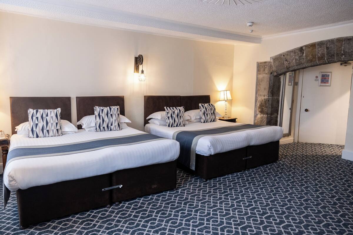 Habitación de hotel con dos camas, un arco de piedra y suelo estampado.