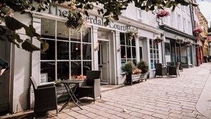 A street view of The Serpentine Court, featuring outdoor seating and hanging flower baskets. - The Allerdale Court Hotel (Cockermouth)