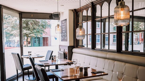 A restaurant interior with wooden tables, leather seating, and large windows. - The Allerdale Court Hotel (Cockermouth)