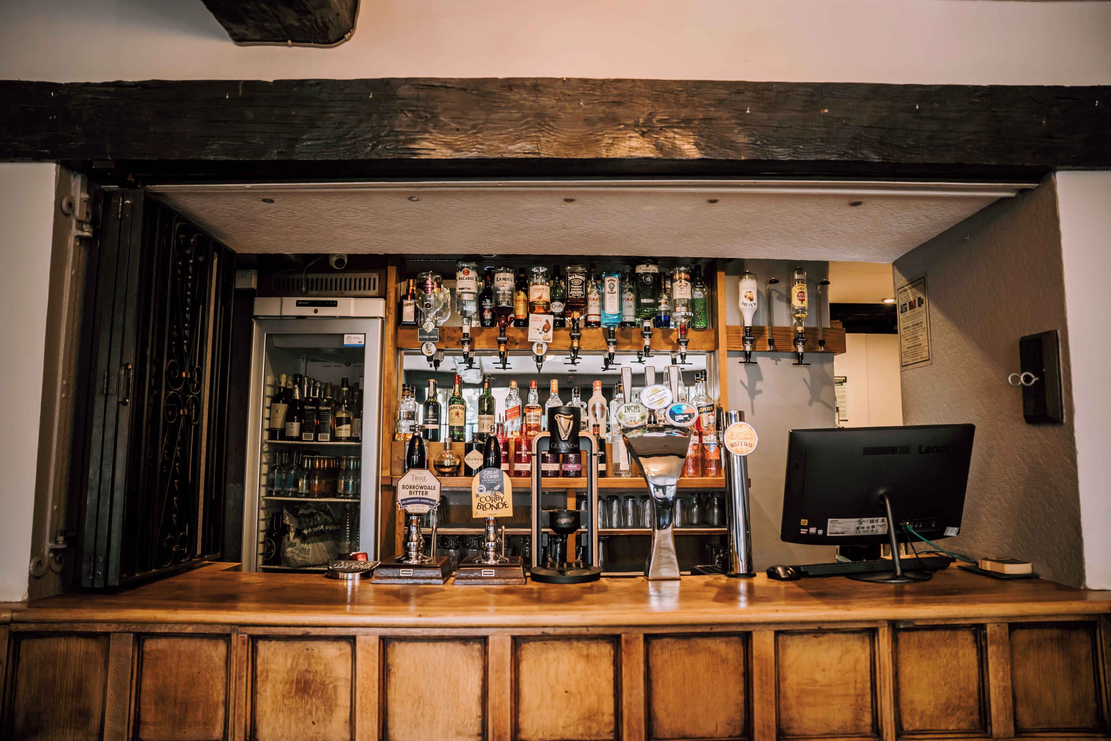 A bar area with a variety of liquor bottles, a television, and a computer monitor.