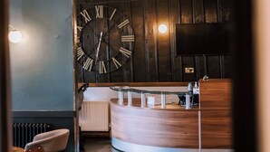 A modern kitchen with a large clock, wooden cabinets, and a round bar area. - The Allerdale Court Hotel (Cockermouth)