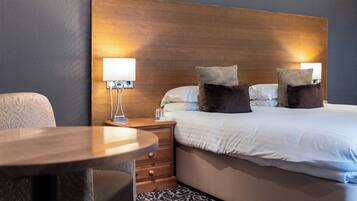 A hotel room with a bed, bedside tables, a lamp, and a patterned carpet.