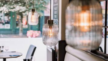 Een restaurantinterieur met hangende吊灯, een houten tafel en een beklede bank.