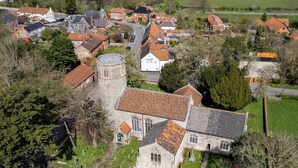 Ein Luftbild eines Dorfes mit einer markanten Kirche, einem Turm und einem Friedhof.