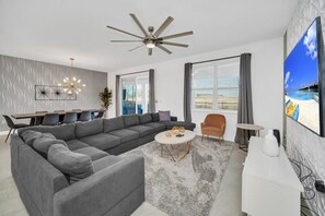 Relax in this spacious living room with a large sofa, flat-screen TV, and dining area.