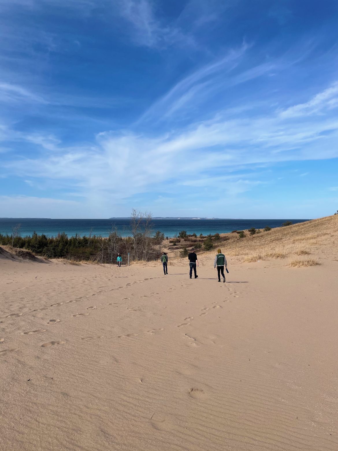 A sandy beach with footprints leading towards the water.